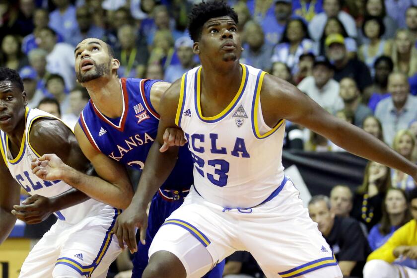 UCLA forward Tony Parker and guard Aaron Holiday battle Kansas forward Perry Ellis for rebounding position during a game Tuesday.