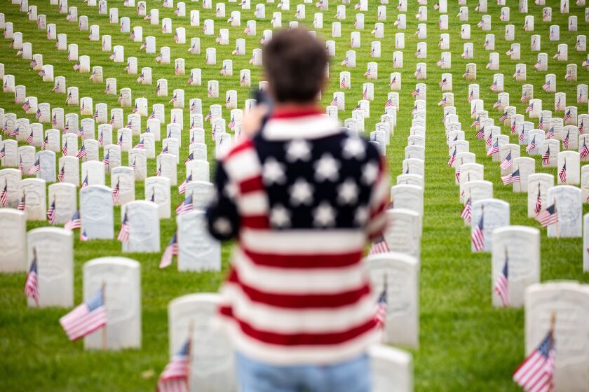 Los Angeles, CA - May 29: A man wearing a flag-adorned sweater, stops to take a picture on Memorial Day, at the Los Angeles National Cemetery, in Los Angeles, CA, Monday, May 29, 2023. (Jay L. Clendenin / Los Angeles Times)