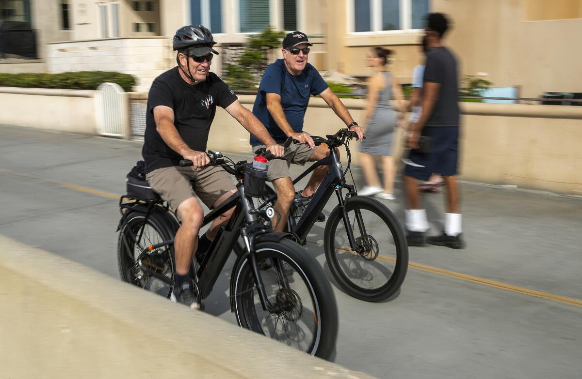 People ride e-bikes in Hermosa Beach.