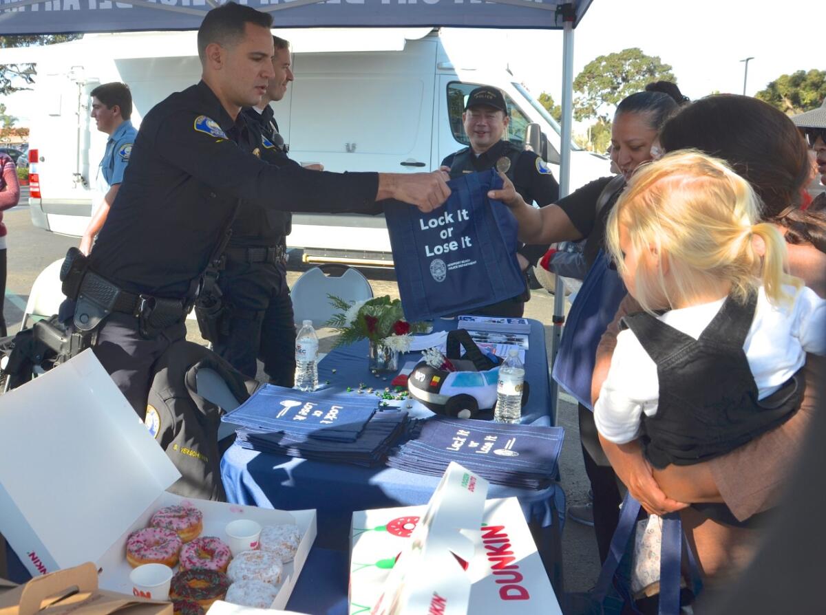 Newport Beach Police Officer Zack Varela hands out bike helmets and tote bags.