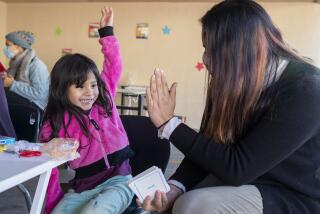 VAN NUYS, CA - NOVEMBER 09, 2020: Nikki Perez, project manager for Kids First celebrates with a 4 year old transitional kindergartner after she successfully learns to say different colors in English and Spanish at a learning pod for homeless children, located in the carport at the Hyland Motel in Van Nuys. (Mel Melcon / Los Angeles Times)