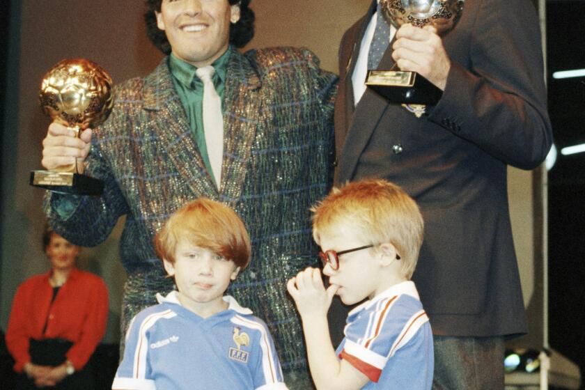 FILE - Argentina's soccer star Diego Maradona, left, and West German goalkeeper Harald Schumacher are holding their World Cup Soccer Ball awards while posing with two young soccer players during the Soccer Golden Shoe Award ceremony held in Paris, France, on Nov. 13, 1986. A trophy won by the late Diego Maradona for the best player at the 1986 World Cup that had mysterioulsy disappeared has resurfaced. It will be auctioned in Paris next month, the Aguttes house said on Tuesday May 7, 2024. (AP Photo/Michael Lipchitz, File)