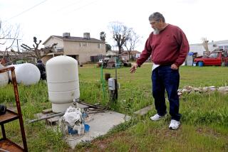 SANGER, CA - FEBRUARY 22: A water well, shown left, went dry in August 2022 on the property of Michael Torres, 66, and wife Anita Torres, 61, not shown, along Fairbanks Ave. in the Tombstone neighborhood, unincorporated Fresno County, on Wednesday, Feb. 22, 2023 in Sanger, CA. Torres bought the property 27-years-ago, living on a smaller home since 1998. He built a new home in 2007 where he lives with his wife and two adult chidren. He signed up with Self Help Enterprises who transport non-potable water to a 2500 gallon tank located on his property. His granddauther is also shown at left. In the community of Tombstone in Fresno County, residents' wells have continued going dry during the drought as nearby farms have heavily pumped groundwater, drawing down the water levels. Residents have lost access to water and are now depending on tanks and deliveries of water by truck. A potential solution for the area would involve connecting to water pipes from nearby Sanger, but progress has been slow. (Gary Coronado / Los Angeles Times)