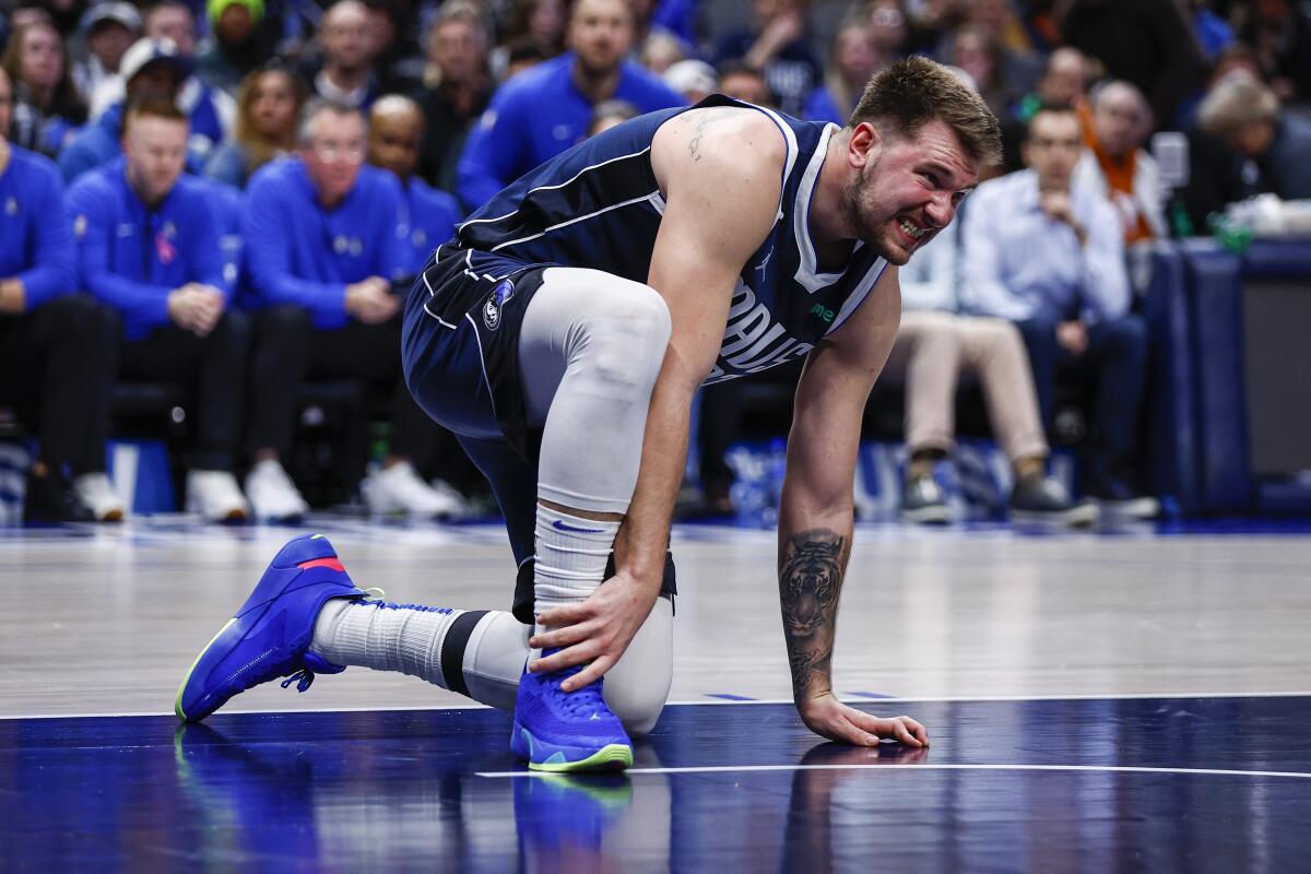 Dallas Mavericks guard Luka Doncic grabs his right foot after an awkward fall during the second half of an NBA basketball game against the New Orleans Pelicans, Thursday, Feb. 2, 2023, in Dallas. Doncic left the game shortly afterward with a right heel contusion. (AP Photo/Brandon Wade)