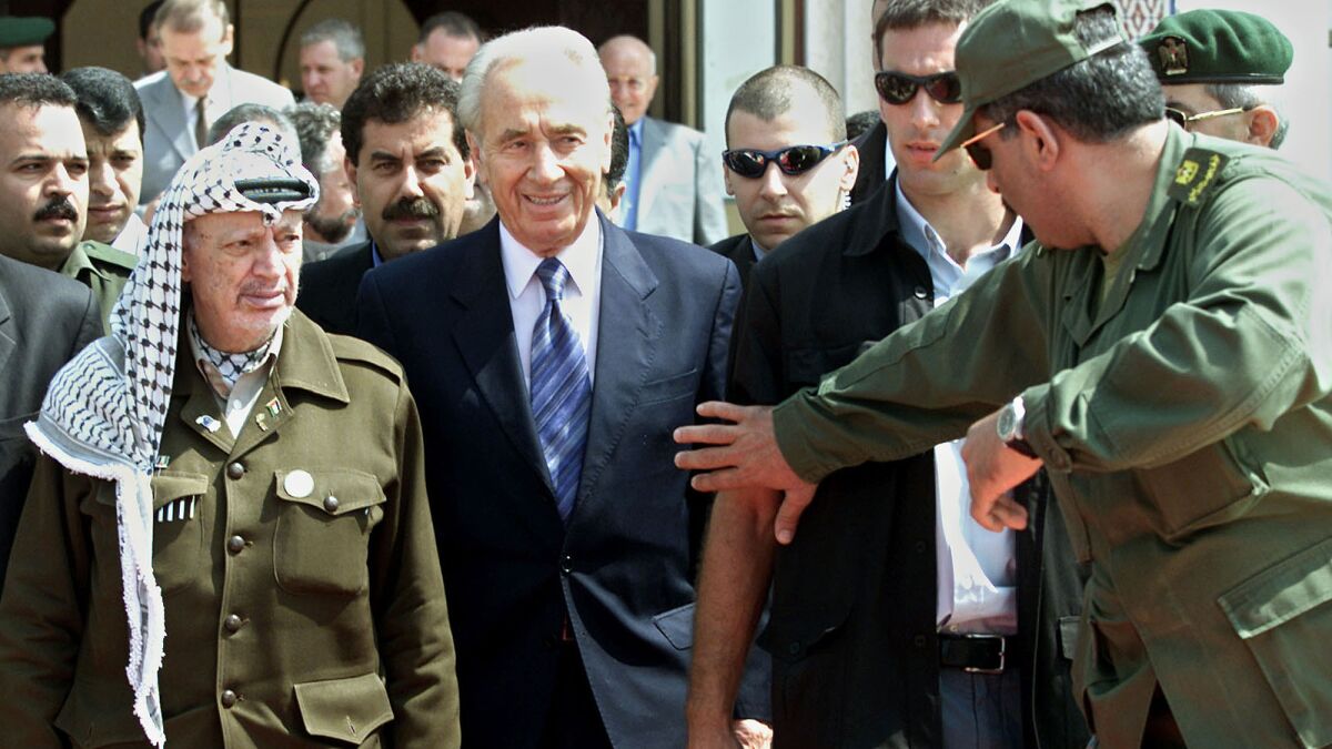 Israeli Foreign Minister Shimon Peres, center, and Palestinian leader Yasser Arafat, left, leave a meeting in the Gaza Strip on Sept. 26, 2001.