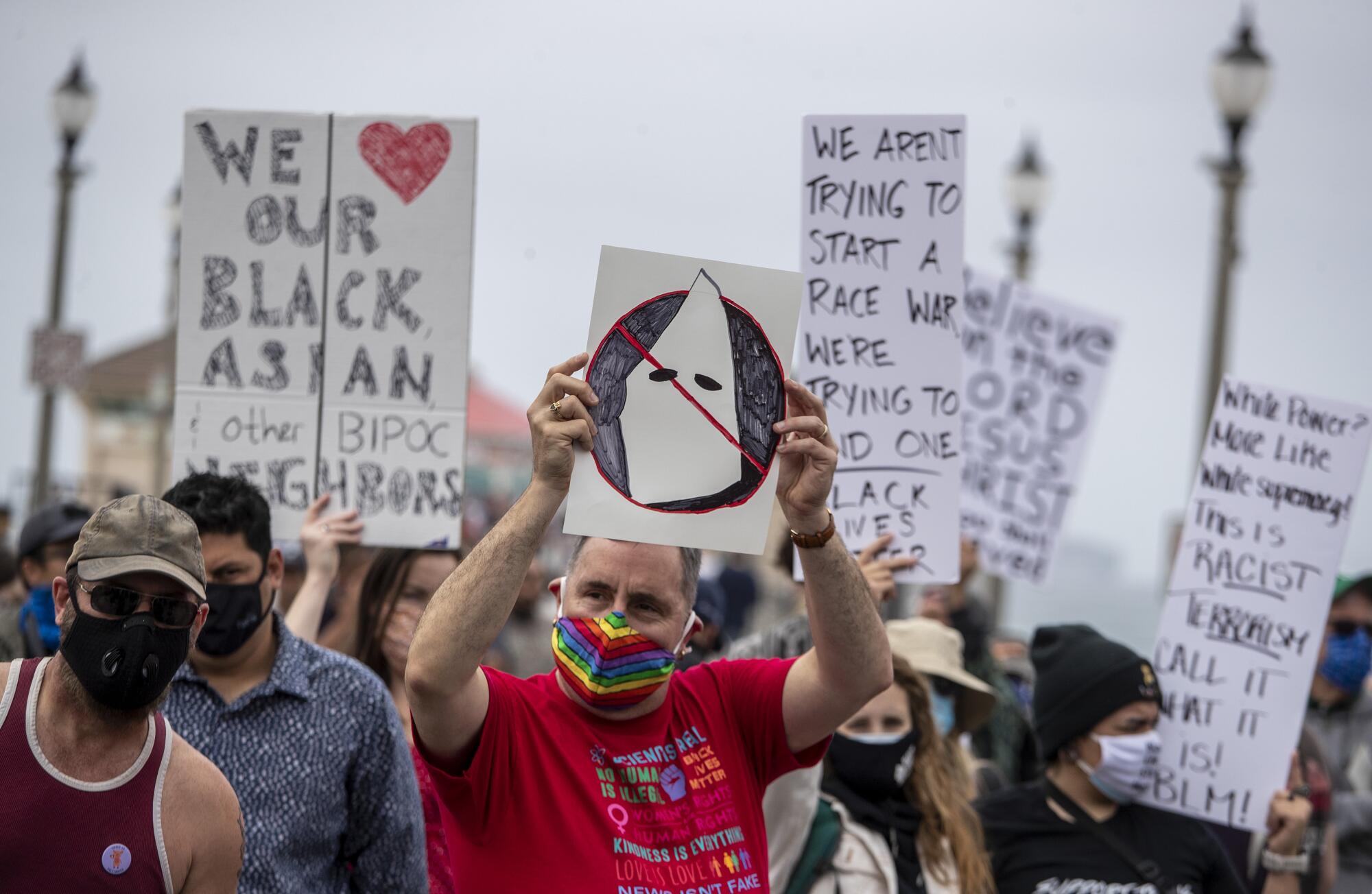 Masked protesters hold signs at a rally