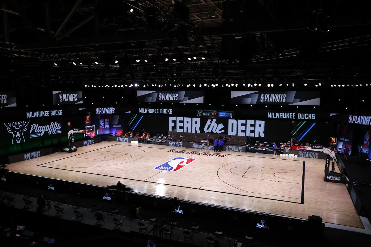 Referees huddle on an empty court for scheduled game between the Milwaukee Bucks and the Orlando Magic on Wednesday.