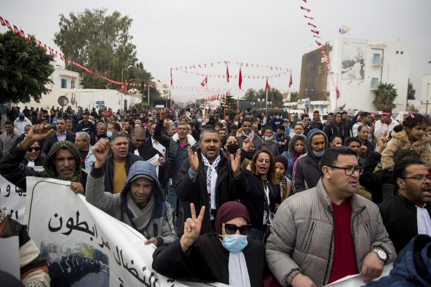 People march and shout slogans as they attend a protest in Sidi Bouzid, Tunisia Thursday, Dec. 17, 2020. Sidi Bouzid, an economically troubled region in central Tunisia, is still waiting to reap rewards from the North African nation's revolution, 10 years after a local fruit and vegetable seller set himself aflame in front of a government building to protest humiliation by police who seized his cartful of merchandise. (AP Photo/Riadh Dridi)