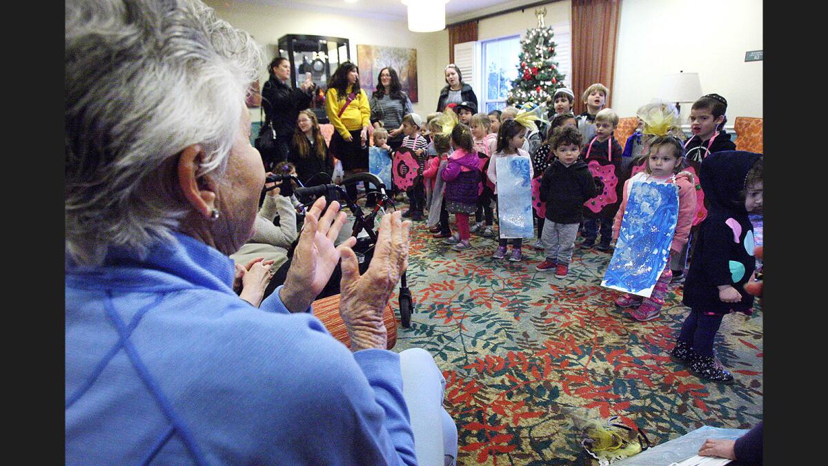 Resident Sonia Most, 87, claps with the children from Chabad Burbank Preschool as they sing songs to residents at Belmont Village Retirement Home.