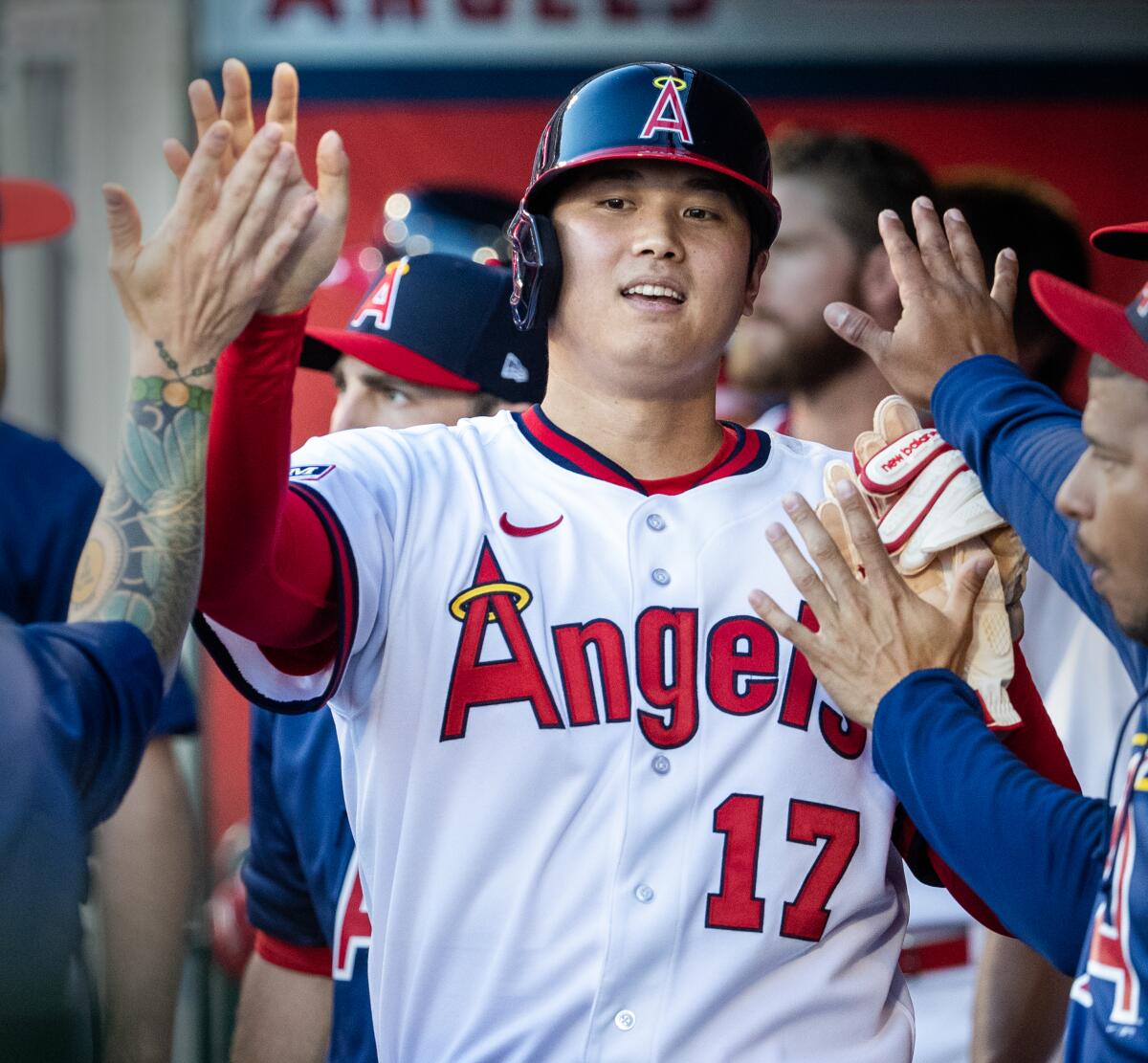 Angels two-way star Shohei Ohtani celebrates with teammates in the dugout after scoring against the Pittsburgh Pirates.