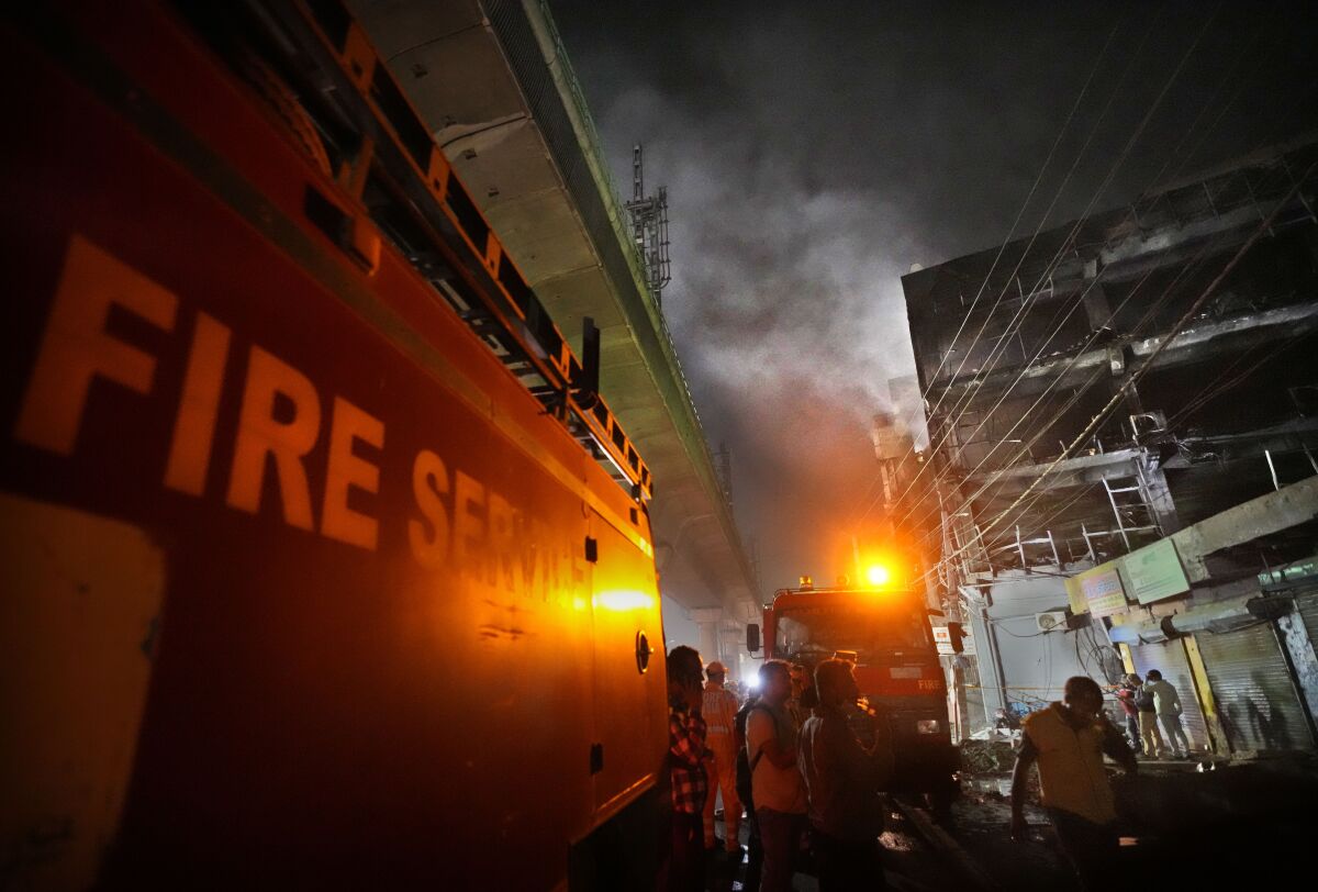 Fire officials try to douse a fire in a four storied building, in New Delhi, India, Saturday, May 14, 2022. A massive fire erupted in a four-storied building in the Indian capital on Friday, killing at least 19 people and leaving several injured, the fire control room said. Dozens of people have been rescued from the commercial building, mainly shops, in the Mundka area in the western part of New Delhi. (AP Photo/Manish Swarup)