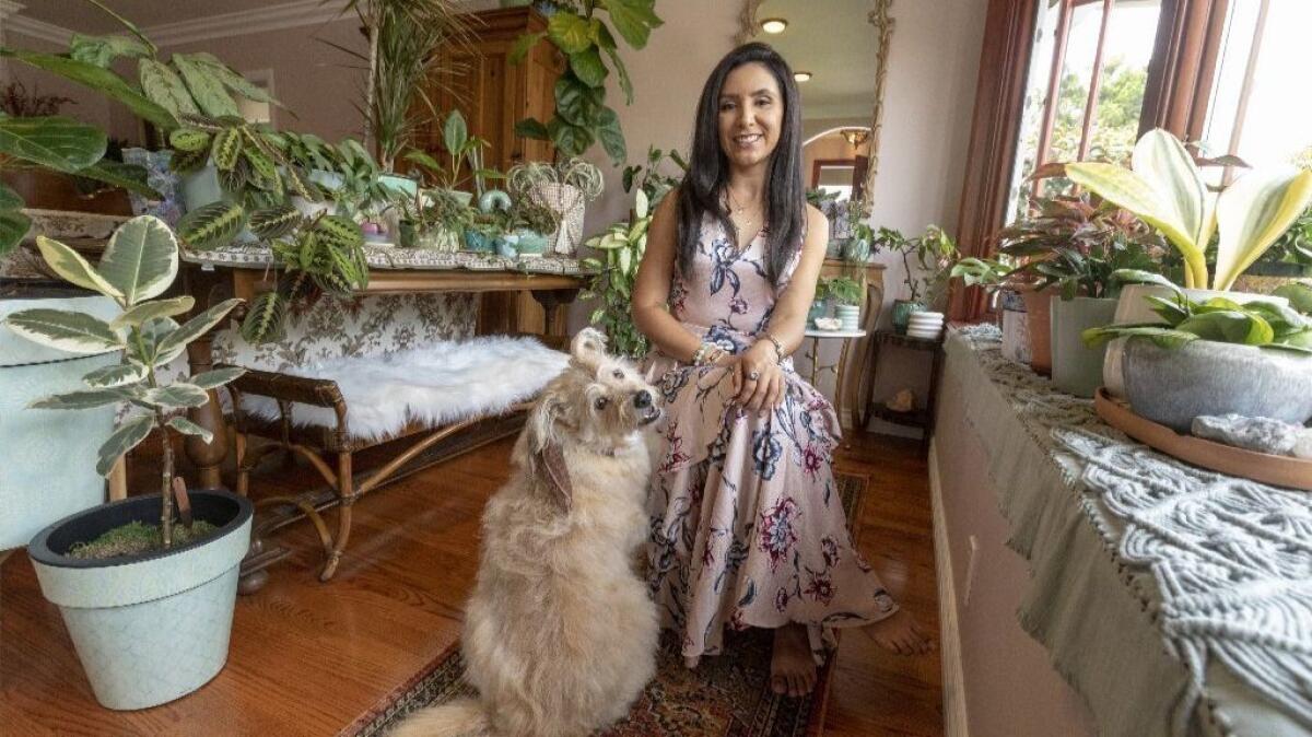 Darlene Zavala, in her living room with her house plants and dog Lialah.