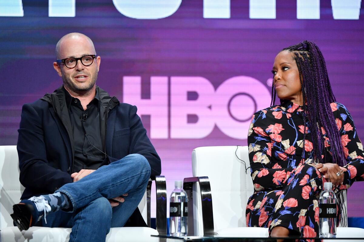 A bald man in glasses and a Black woman speaking at a panel.