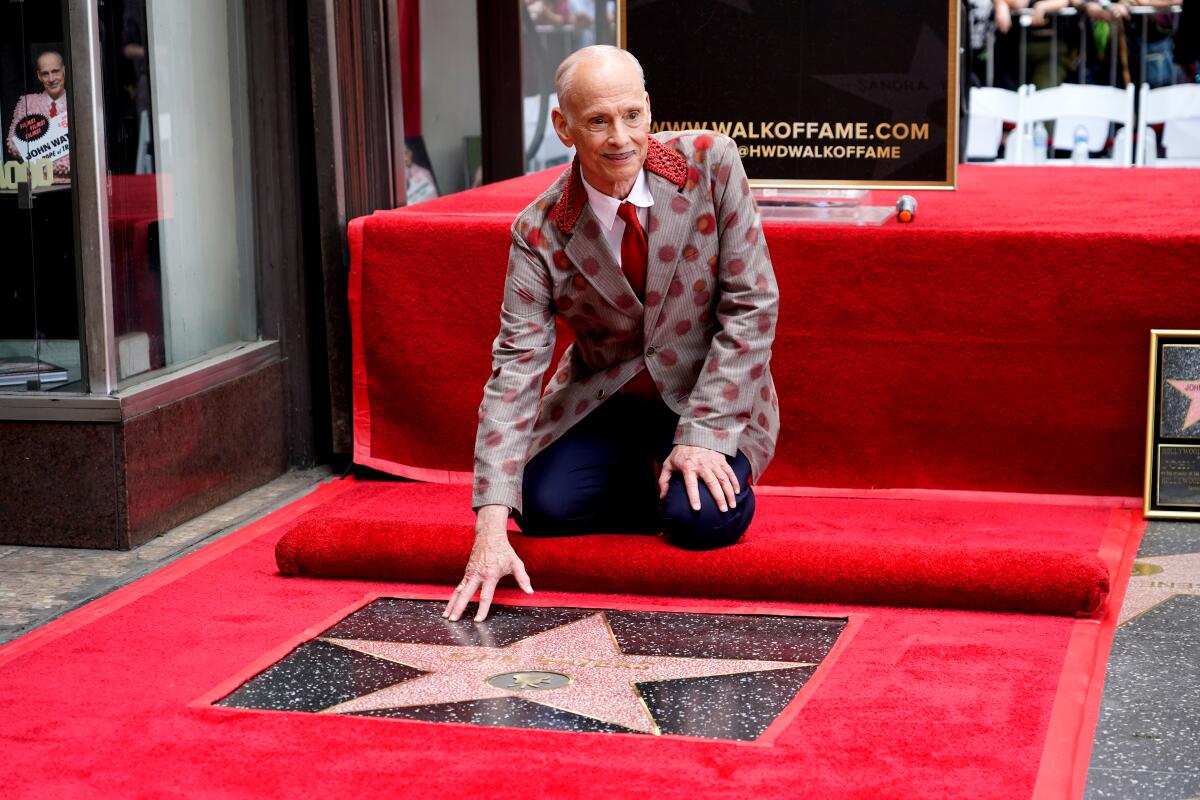 John Waters kneels on the red carpet to touch his new star during a ceremony on the Hollywood Walk of Fame in September.
