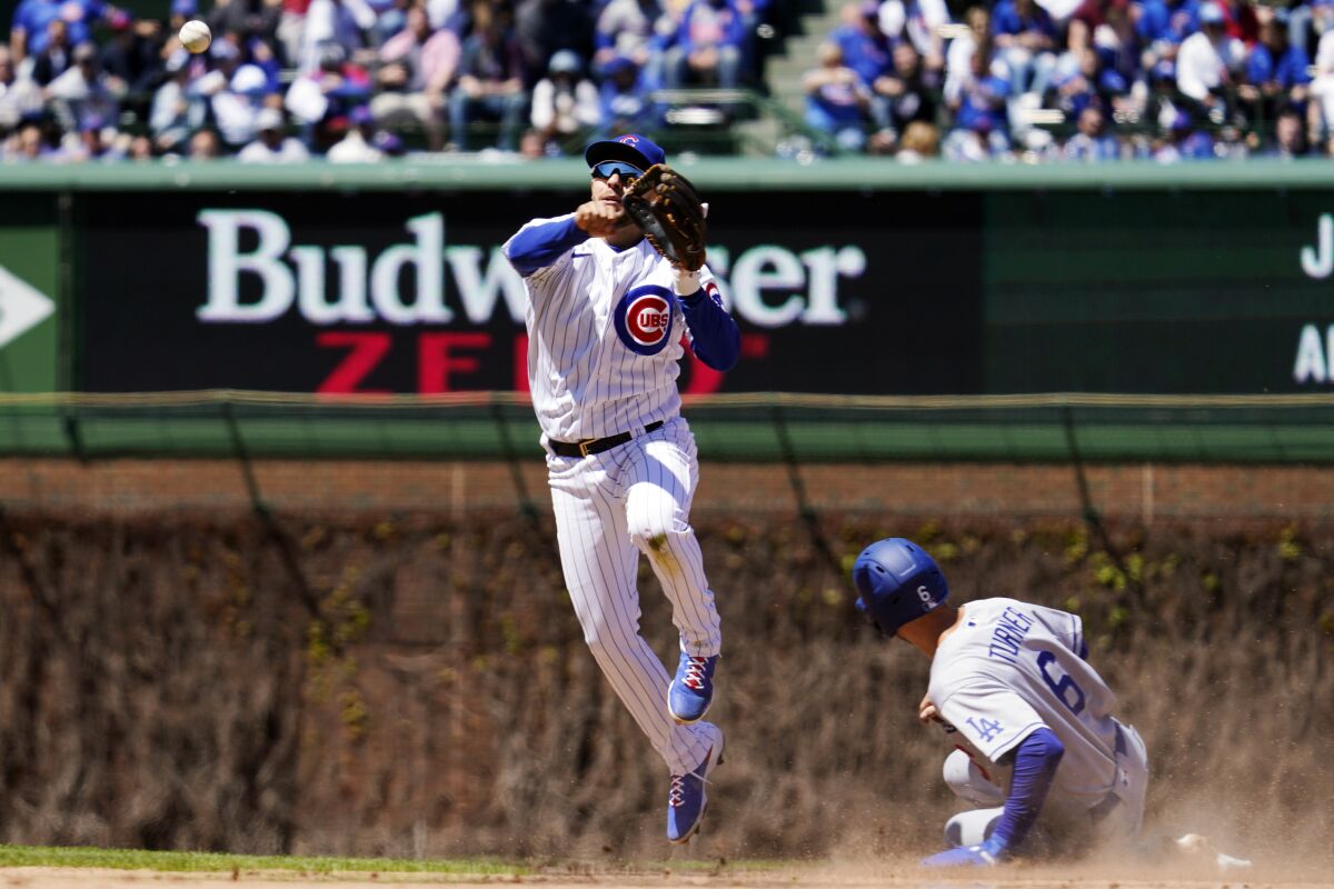 Chicago Cubs second baseman Nick Madrigal, left, throws out Los Angeles Dodgers Justin Turner at first after forcing out Trea Turner at second base during the seventh inning in the first baseball game of a doubleheader Saturday, May 7, 2022, in Chicago. (AP Photo/Nam Y. Huh)