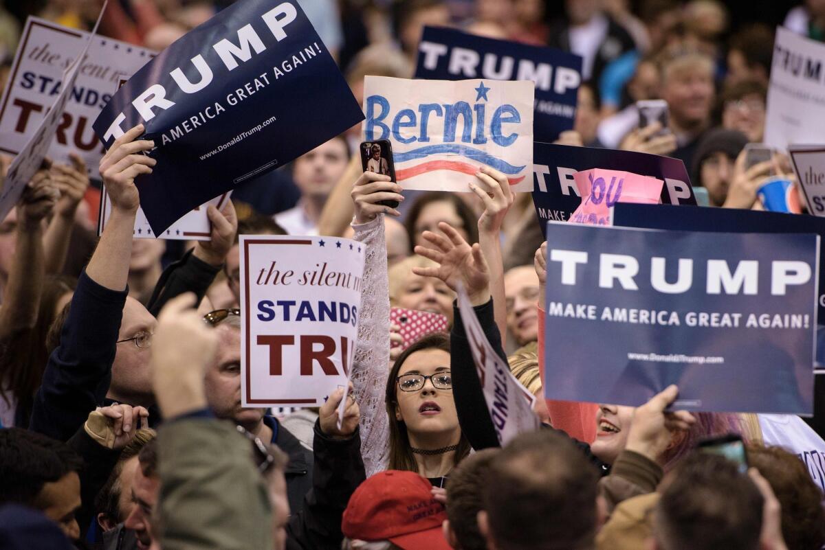 A supporter of Democratic candidate Bernie Sanders holds up a sign during a Donald Trump rally Saturday in Cleveland. The Republican candidate blames Sanders supporters for instigating violence at a Trump event in Chicago, which was canceled for security reasons.