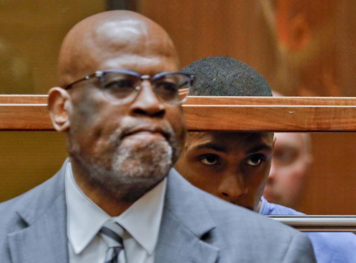 Eric Holder, middle, the suspect in the killing of rapper Nipsey Hussle is seen with his attorney, Christopher Darden, left, in Los Angeles County Superior Court.