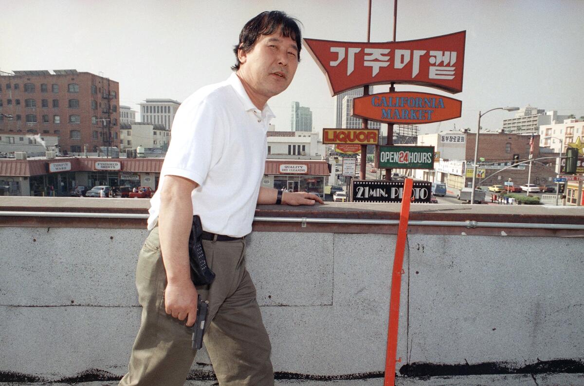 A man holds a gun on a Koreatown rooftop.