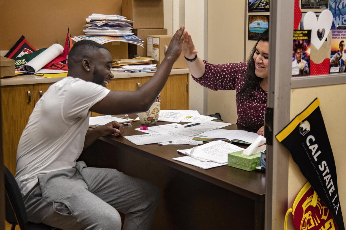 Senior Damion Lester Jr., the valedictorian and student body president, gets a high-five from college counselor Marcy Zaldana at Washington Prep High School in Los Angeles.