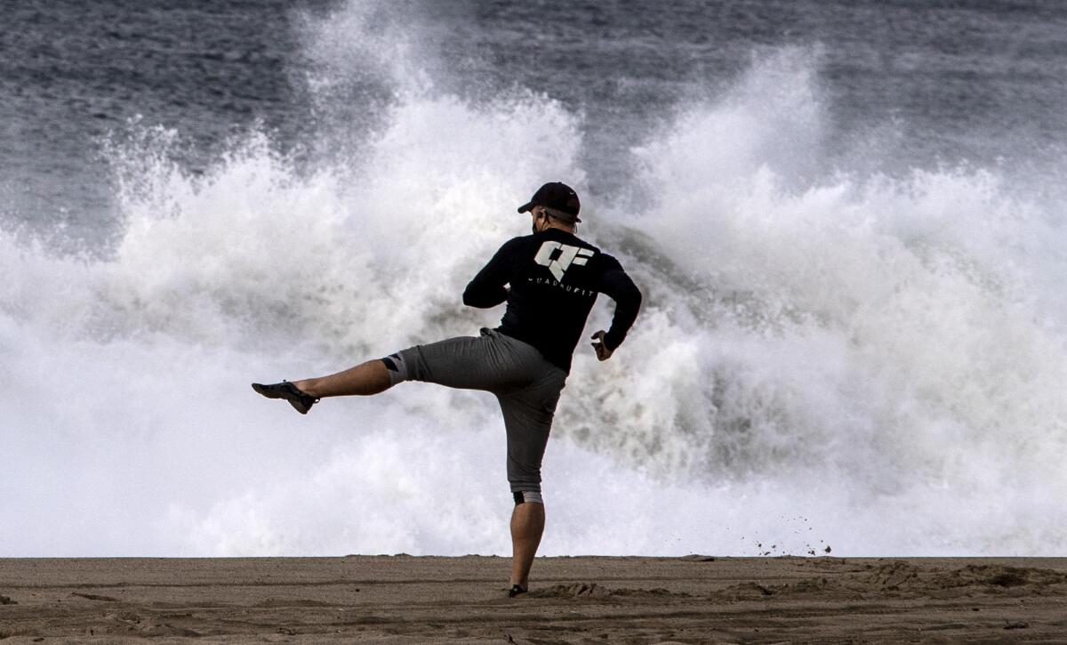 A man does exercises on the beach at Malibu.