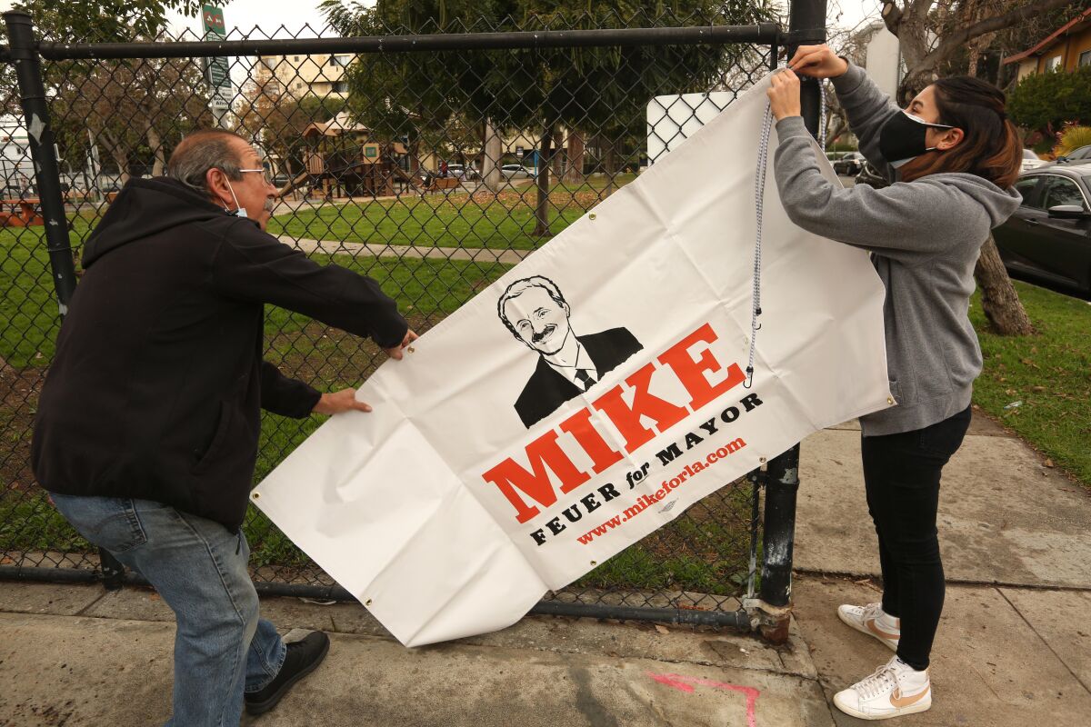 Campaign workers hang a banner before Mike Feuer meets with residents at Woodbine Park.