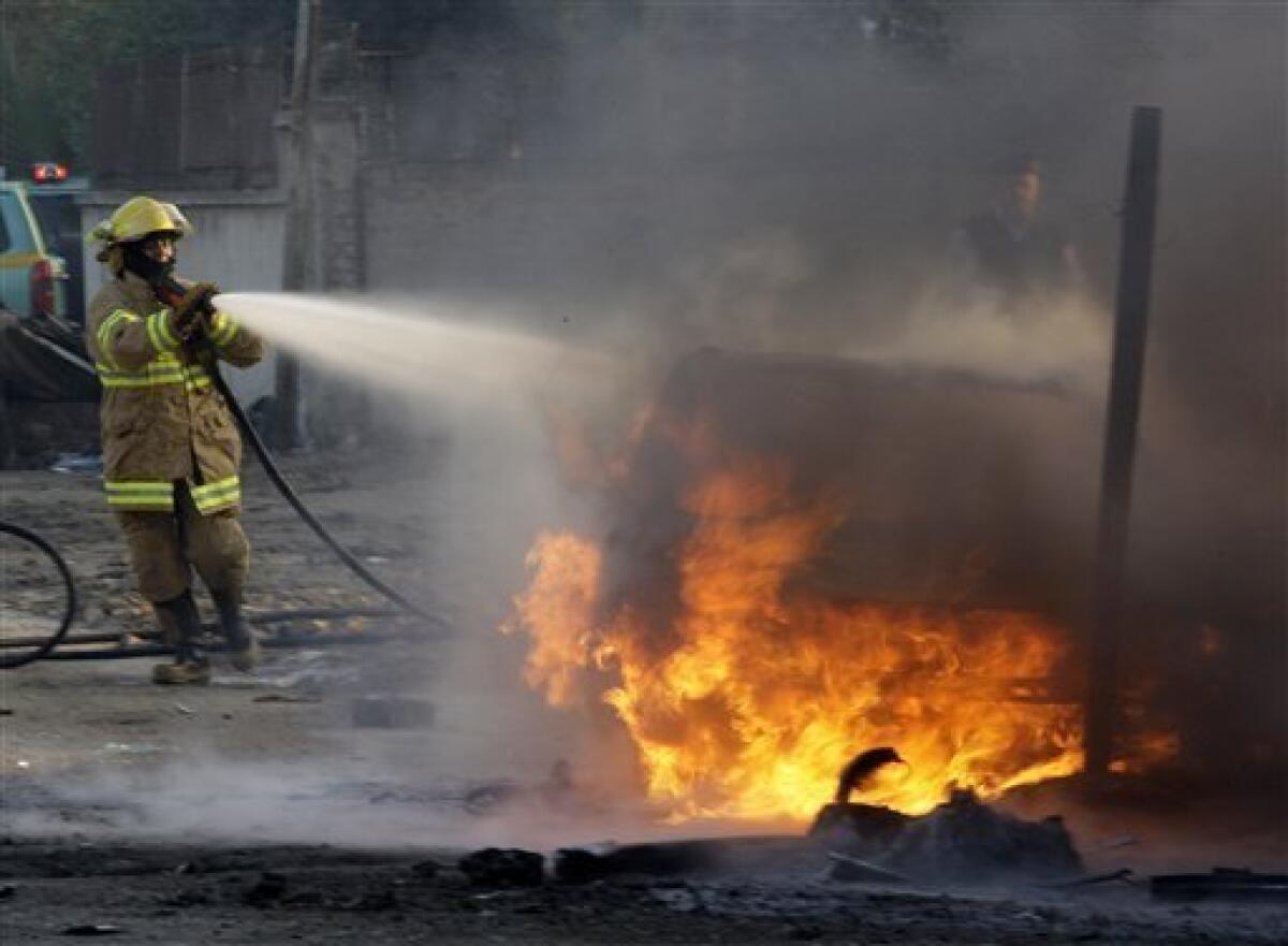 A fire fighter tries to extinguish a fire after a car bomb attack in Baghdad, Iraq, Tuesday, Dec. 15, 2009. A series of car bombs ripped through downtown Baghdad near the heavily fortified Green Zone. (AP Photo/Hadi Mizban)