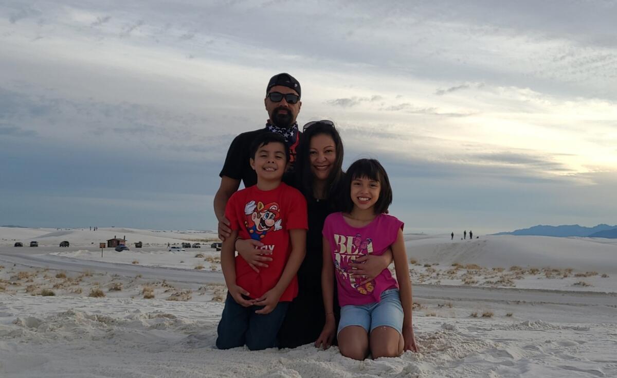 A family of four sits on a beach.