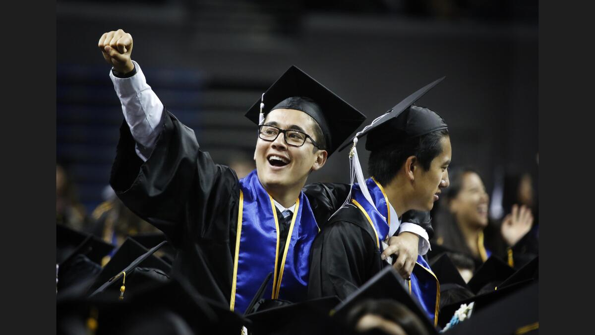 A UCLA student celebrates with a classmate during a graduation ceremony.
