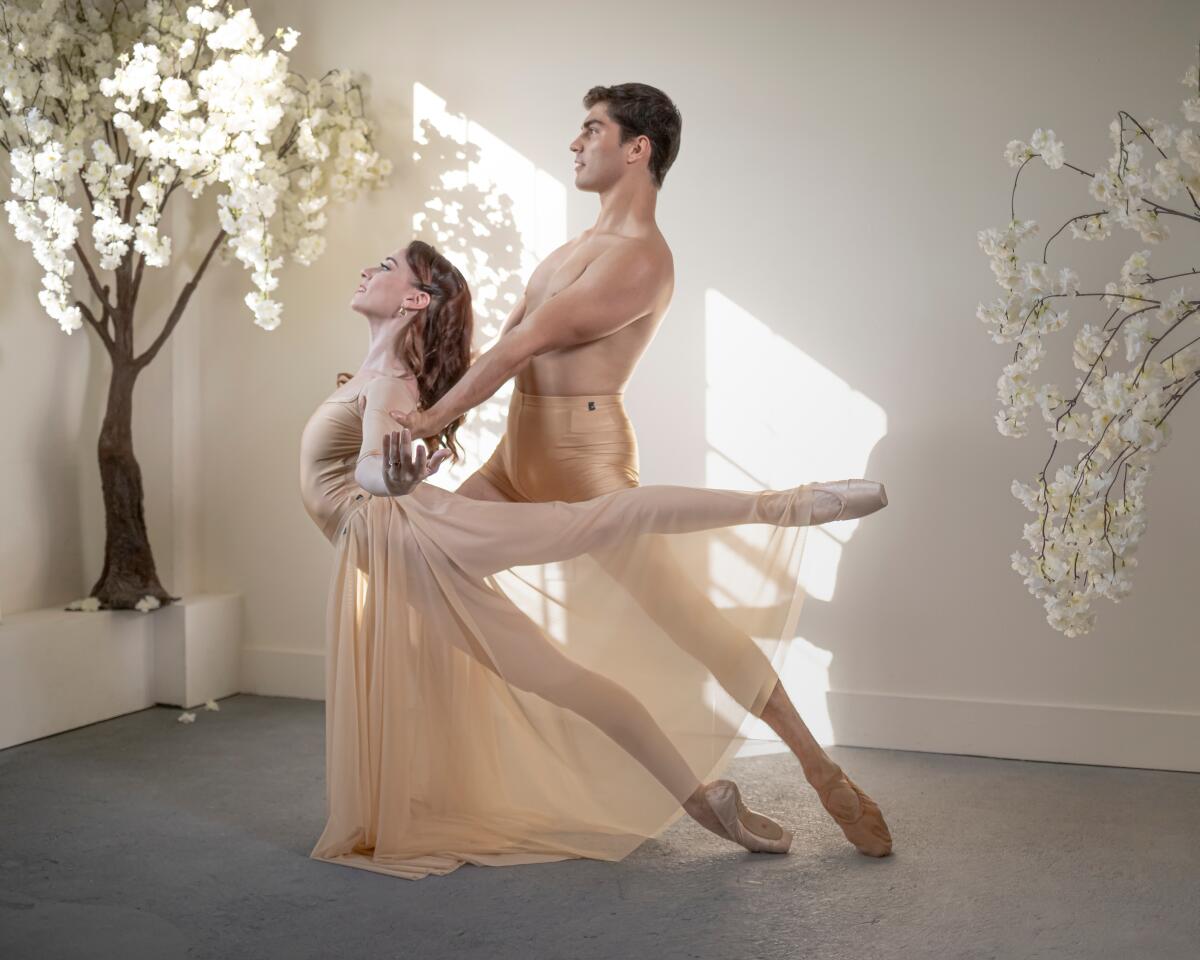 Male and female ballet dancers surrounded by flowering trees