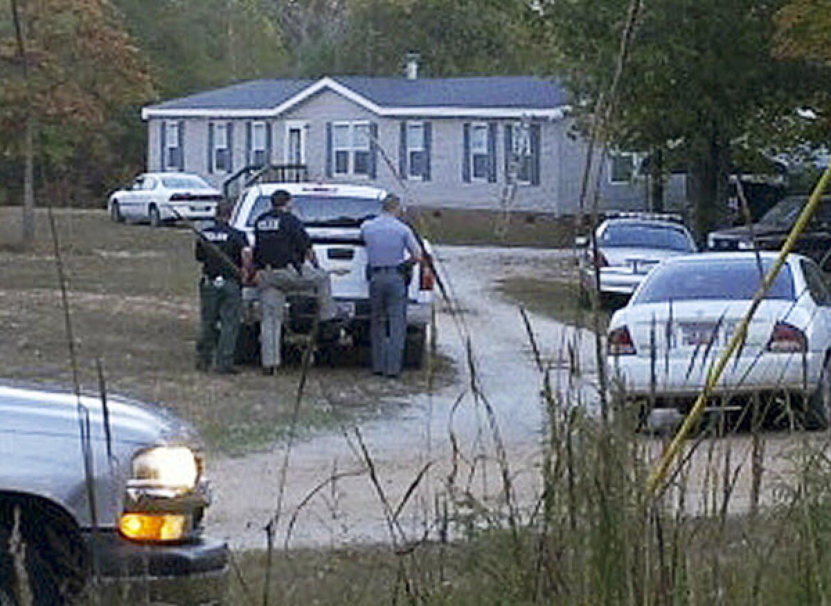 Law enforcement officials stand near a home on Callison Highway where six people were found dead, Tuesday in Greenwood, S.C.