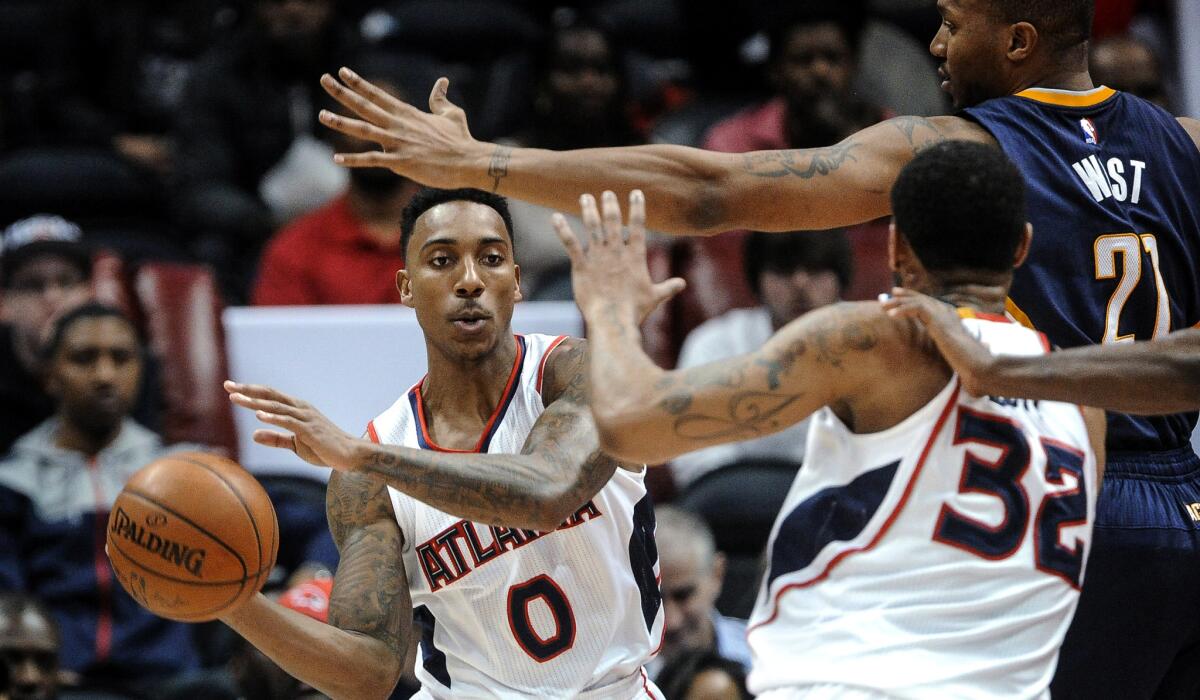 Hawks guard Jeff Teague (0) looks to pass to forward Mike Scott (32) against the pressure of Pacers forward David West (21) in the first half Wednesday night.