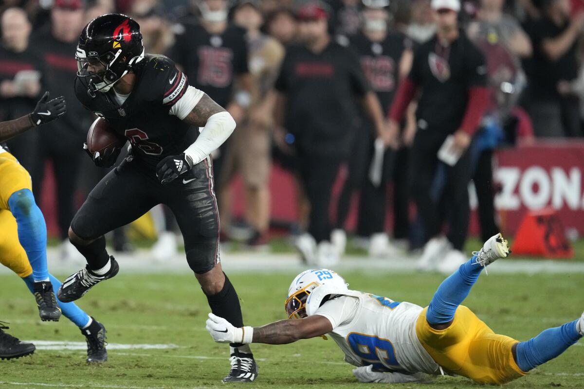 Chargers cornerback Tarheeb Still reaches for the Cardinals' running back.