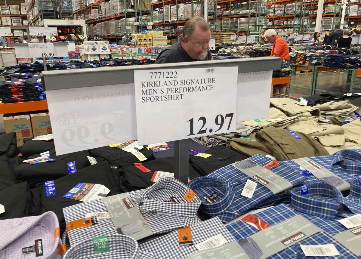A sign displays the price for shirts as a shopper peruses the offerings at a Costco warehouse.
