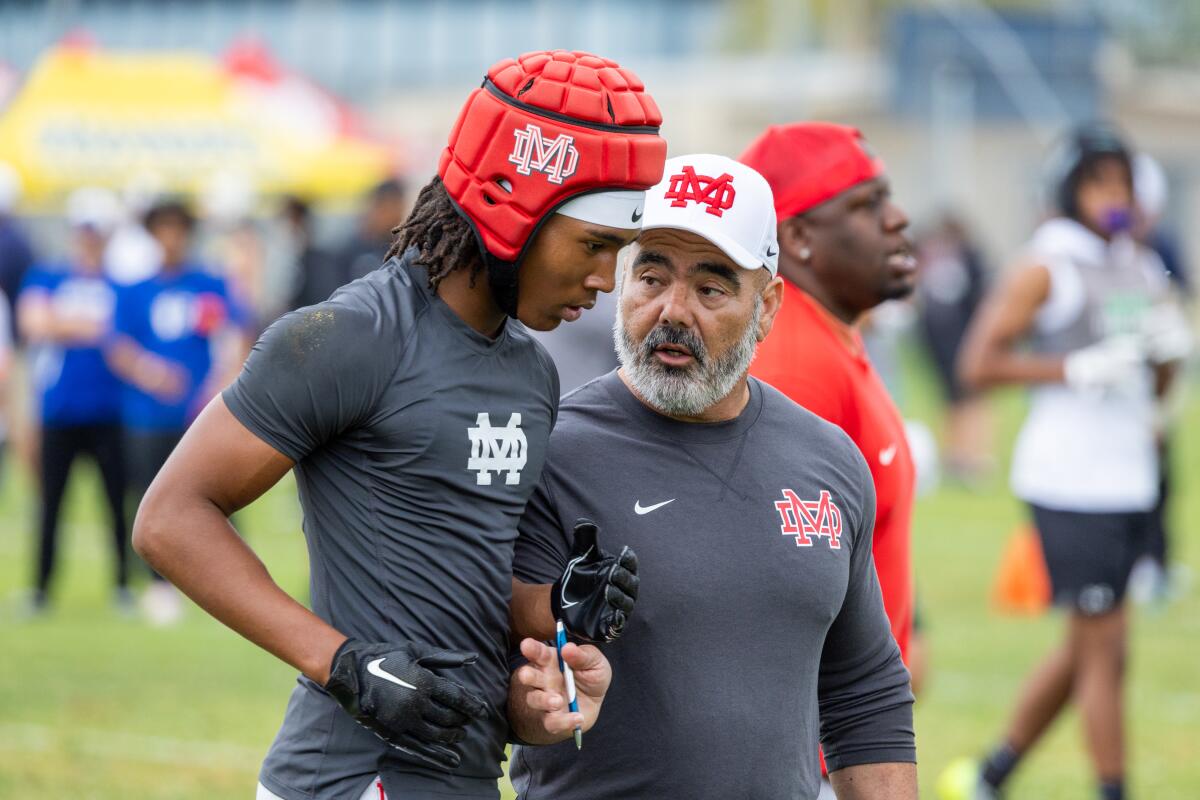 Mater Dei football coach Raul Lara, right, talks to Mater Dei cornerback Patrick Hall after a passing game against Upland.