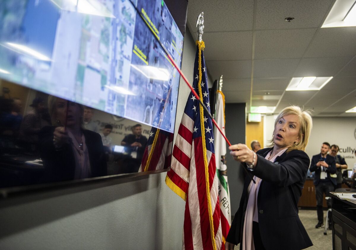 District Attorney Anne Marie Schubert uses a pointer to point to a spot on a satellite map on a TV screen