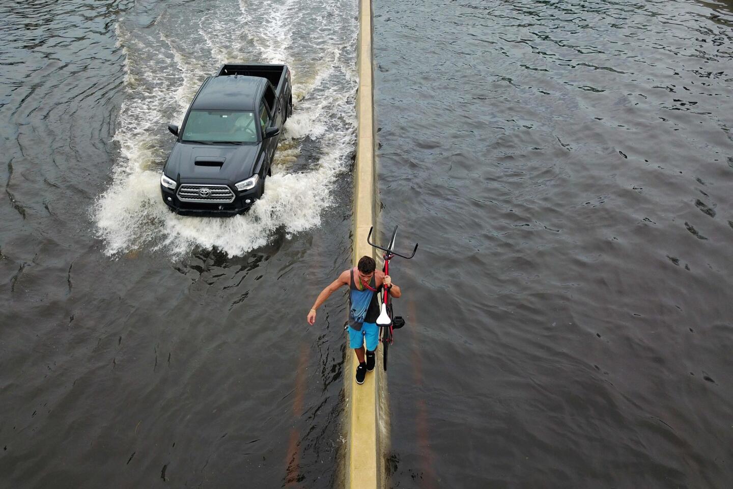 A man walks on a highway divider while carrying his bicycle in the aftermath of Hurricane Maria in San Juan, Puerto Rico.