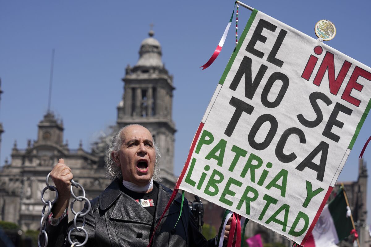 رجل يحمل سلاسل في يد وعلامة باللغة الإسبانية في اليد الأخرى 