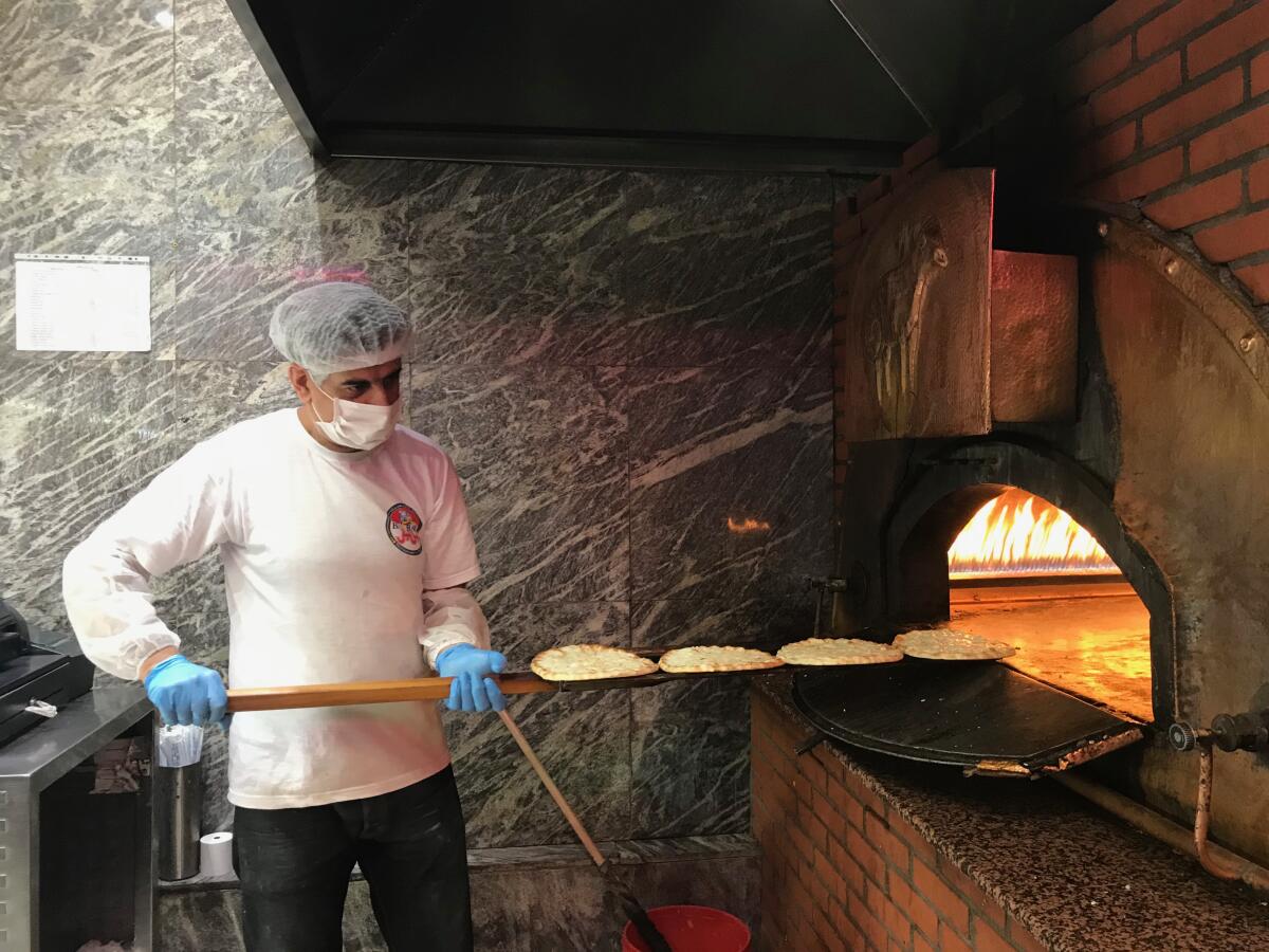 Kamal, one of Barbar's remaining bakers, slides flatbread into the brick oven while making manousheh, a kind of Lebanese pizza.