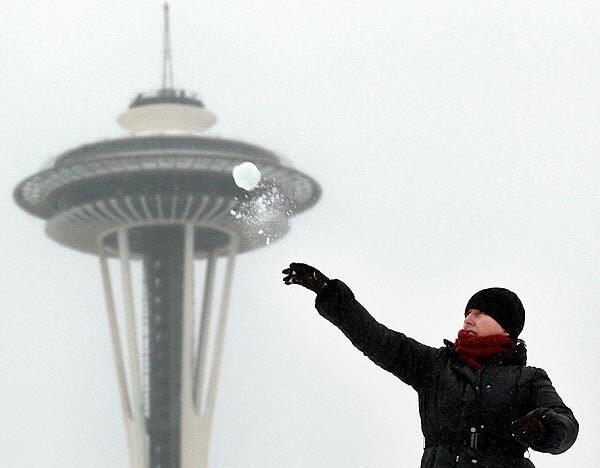 With the Space Needle in the background, Lynne Wyllie tosses a snowball in a downtown Seattle park.