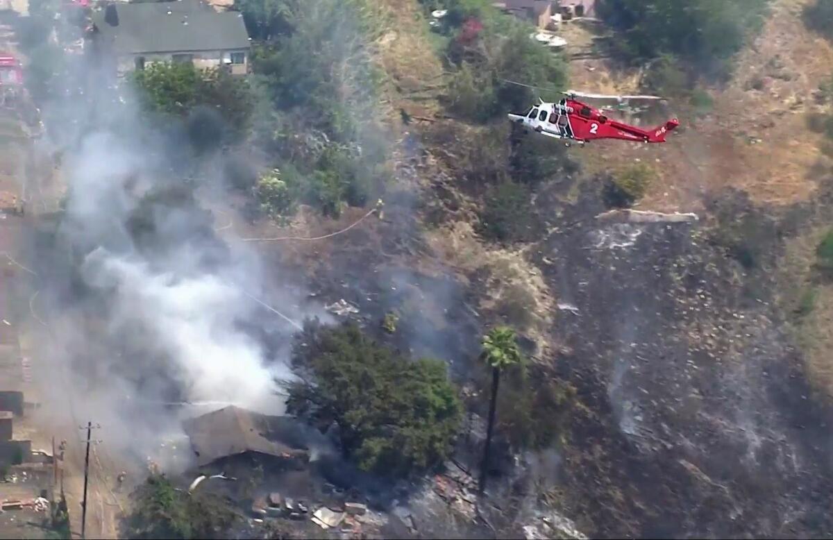 A helicopter flies over a burned area in Lincoln Heights.