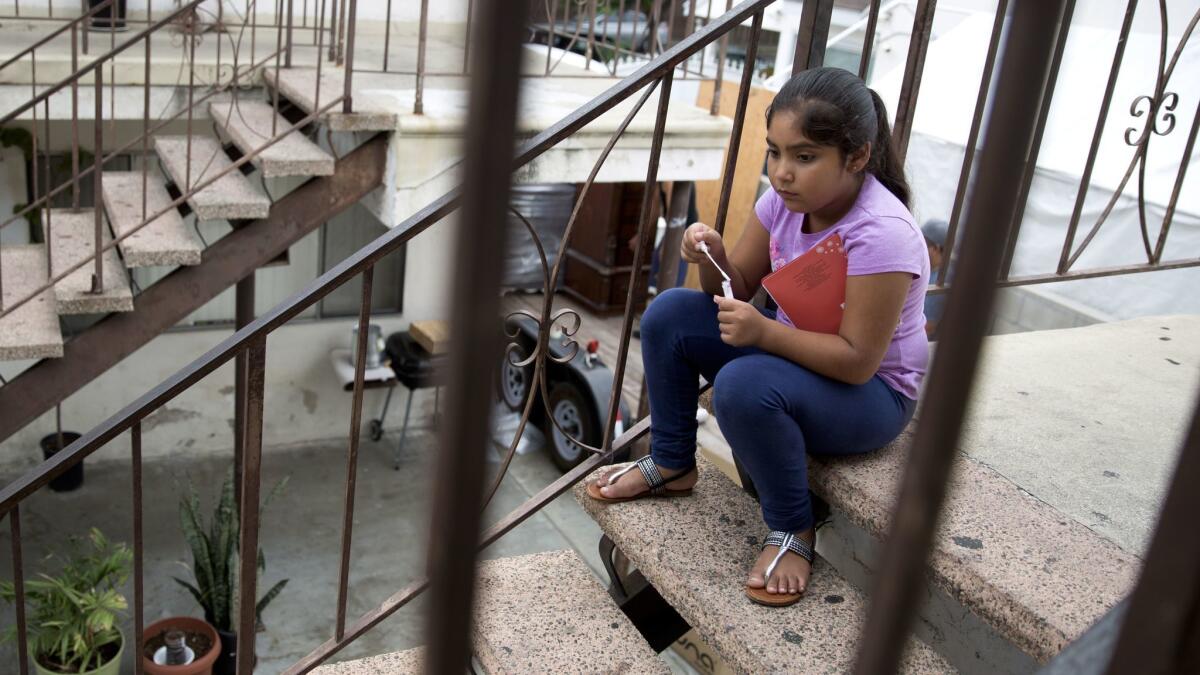 As her family packs the car to move, Luz Madrigal, sits on the steps of her apartment in Gardena. (Brian van der Brug / Los Angeles TImes)