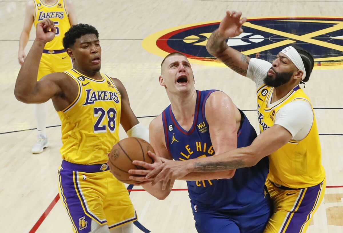 Nikola Jokic, center, tries to power his way through the double-team defense of Anthony Davis, right, and Rui Hachimura.