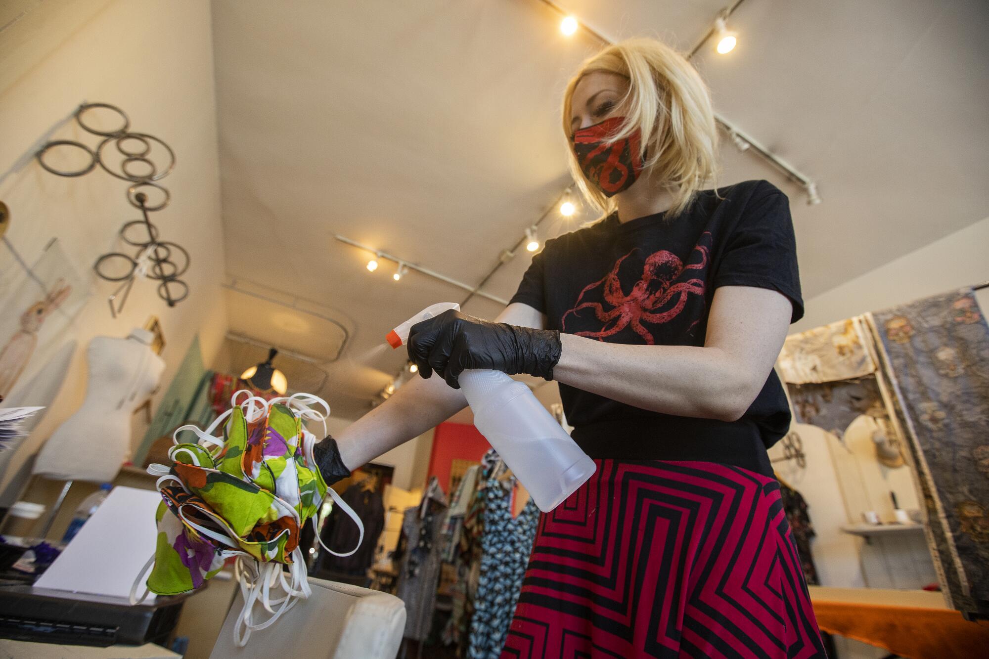 Christine Flick sprays disinfectant on masks before individually bagging them and preparing for shipment