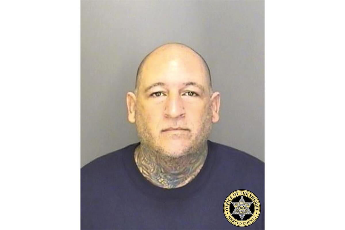 Mugshot of man with shaved head and tattoos around his neck.