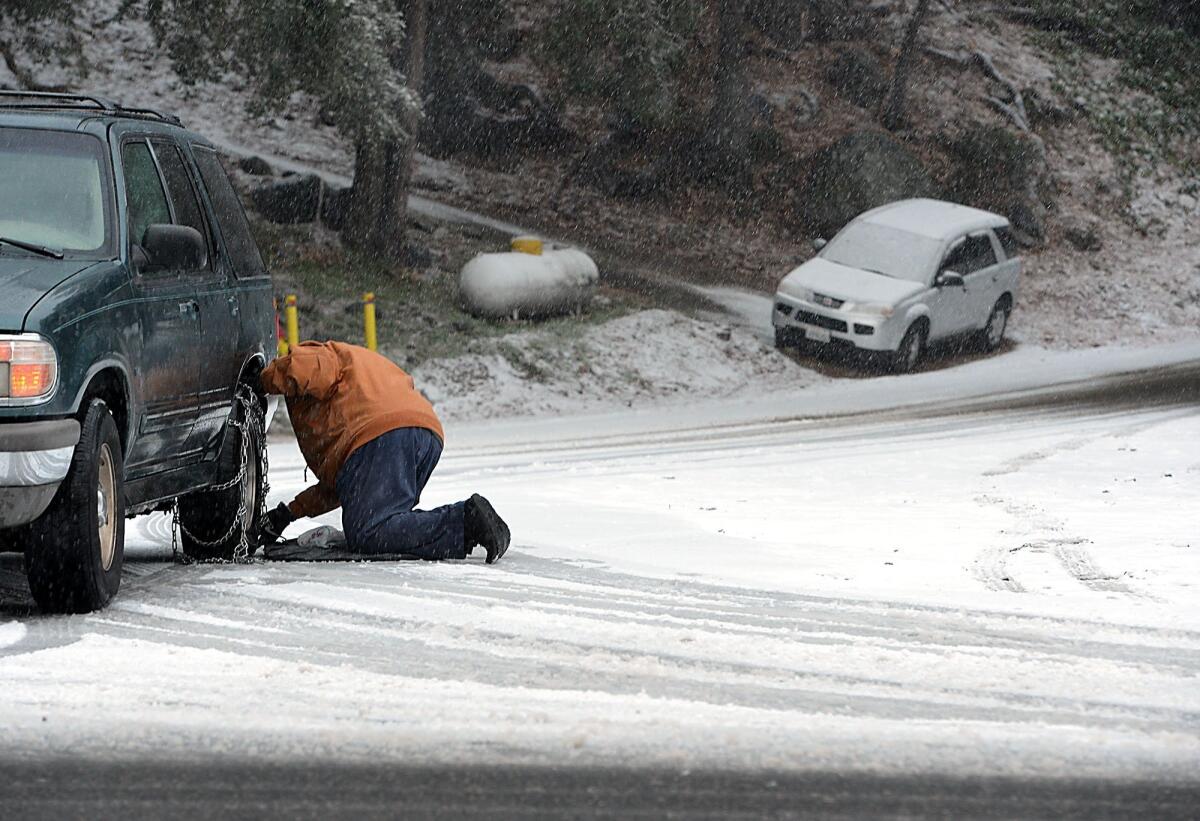 A driver puts chains of his vehicle Tuesday before heading to his home in Forest Falls.