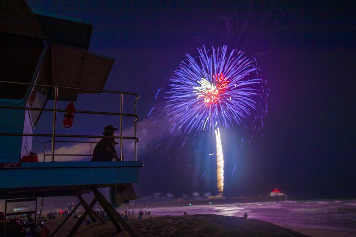 Socorristas observan un espectáculo de fuegos artificiales en el muelle de Huntington Beach el 4 de julio de 2021.
