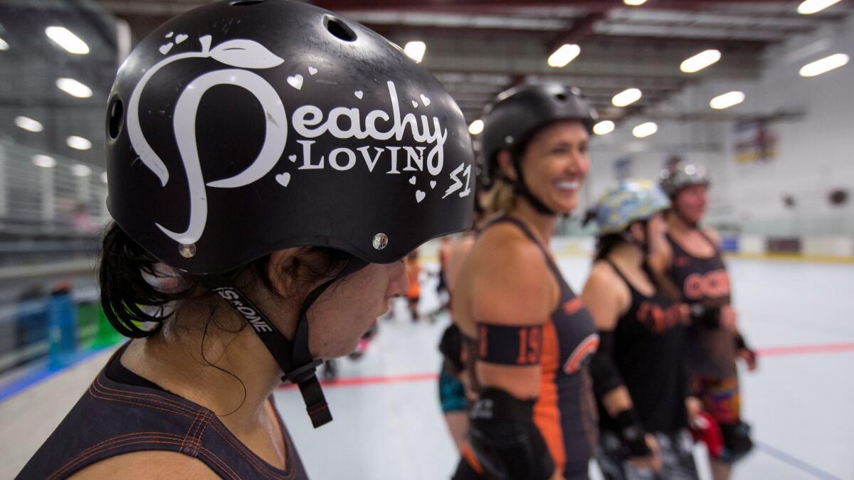 Orange County Roller Derby league skaters' nicknames are proudly displayed on their helmets.