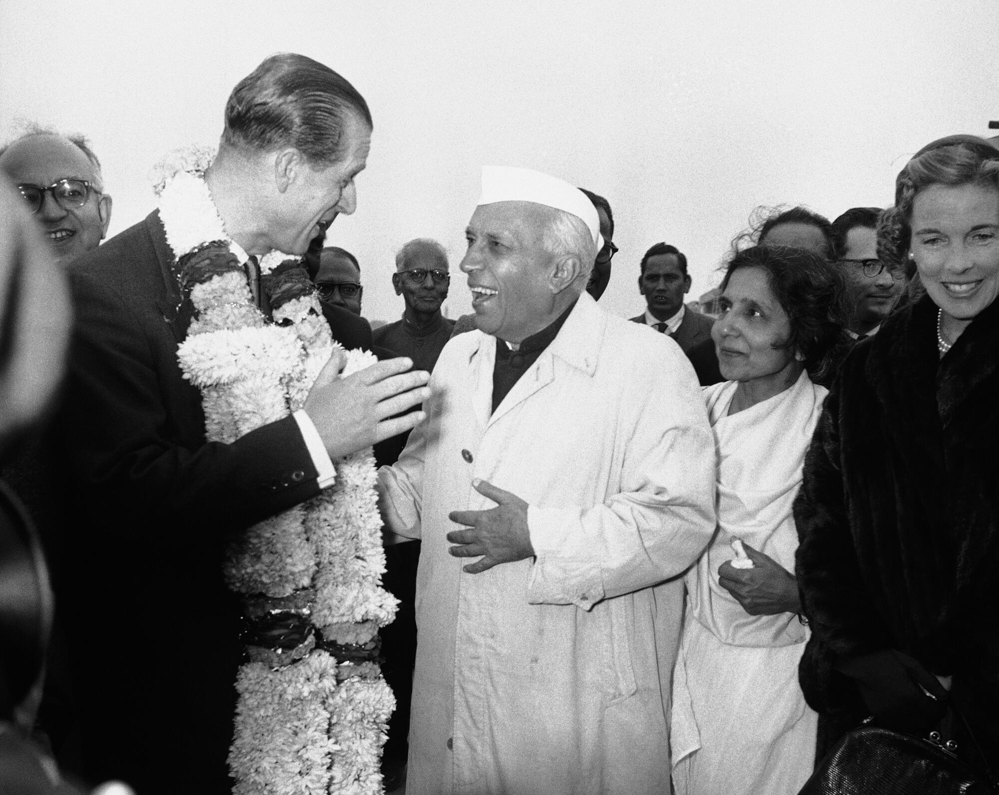 Prince Philip wears a ceremonial garland as he speaks to India's premier.