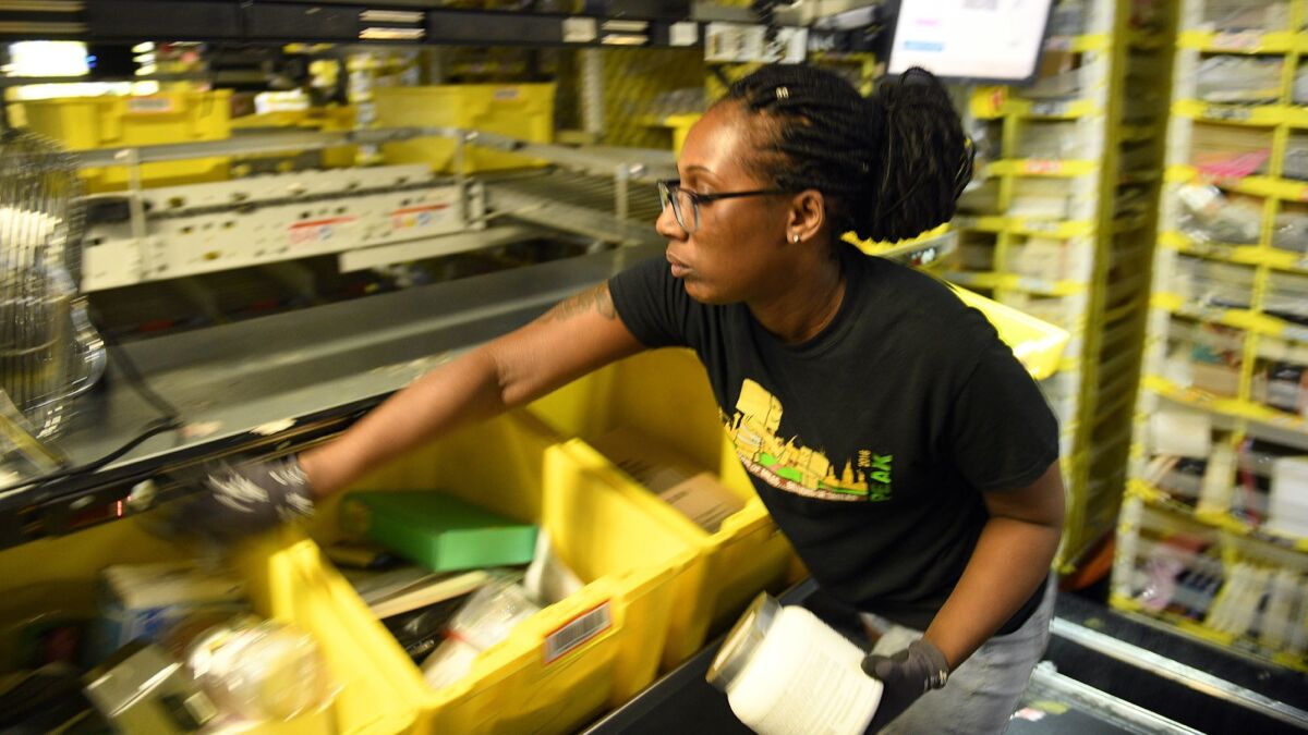 Worker Jackie Spence places ordered products into bins at an Amazon warehouse in Baltimore in May.