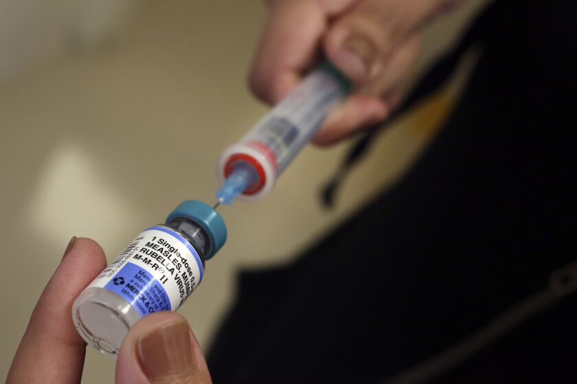 A vial containing the measles vaccine is loaded into a syringe before being given to a child at a local medical center this month.